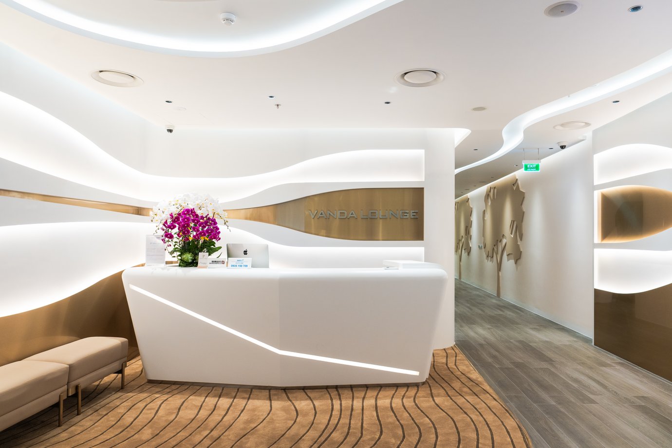 Reception area of Vanda Lounge at Da Nang International Airport Terminal 2, featuring elegant white interior design, curved lighting, and orchid display.