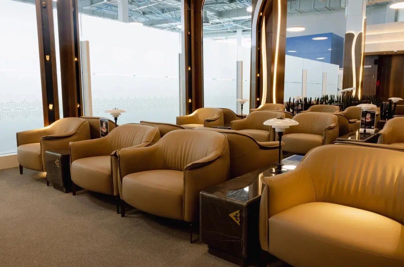 Air Astana Lounge Almaty Airport seating zone with elegant tan leather chairs, soft lighting, and modern wooden accents.
