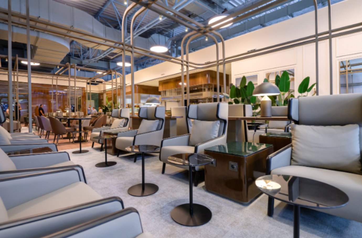 Modern seating area inside the Extime Business Lounge at Almaty International Airport, featuring plush grey recliners with personal tables, soft lighting, and contemporary decor.