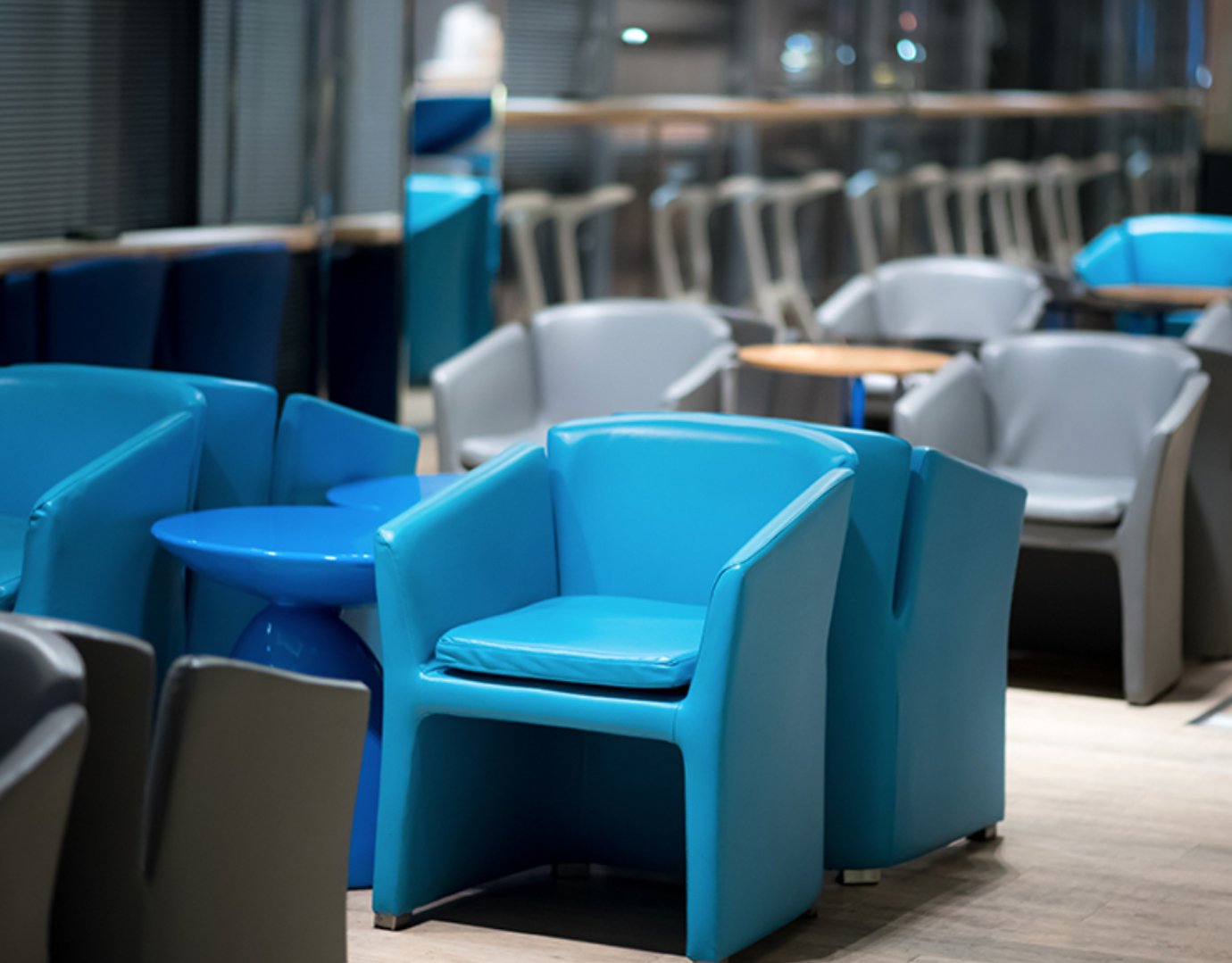 Bangkok Airways Boutique Lounge seating area at Suvarnabhumi Airport with blue and grey armchairs arranged around modern tables.