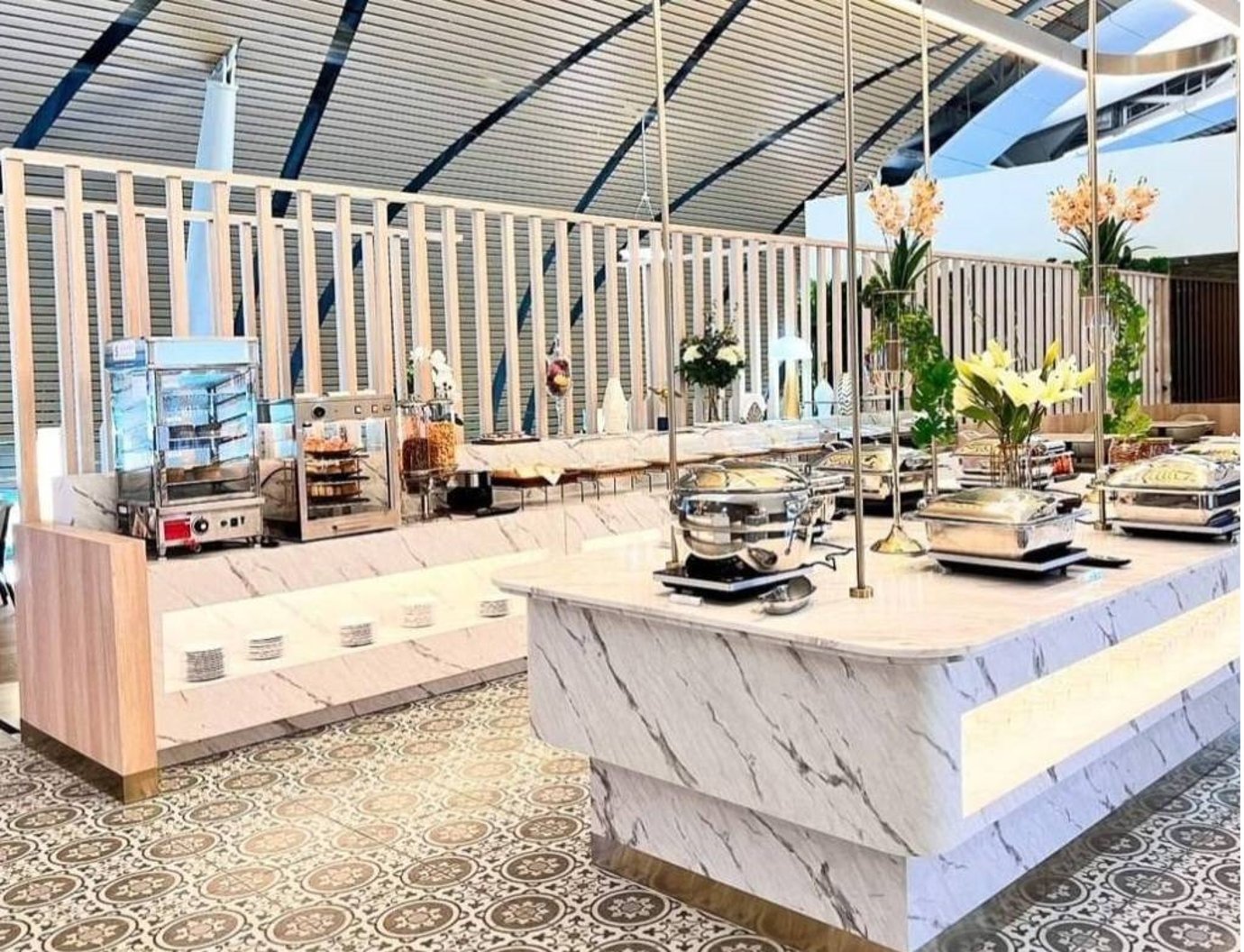 Buffet station at Miracle Business Class Lounge Satellite 1 Bangkok Suvarnabhumi Airport featuring marble counters, hot dishes, and elegant floral decor.