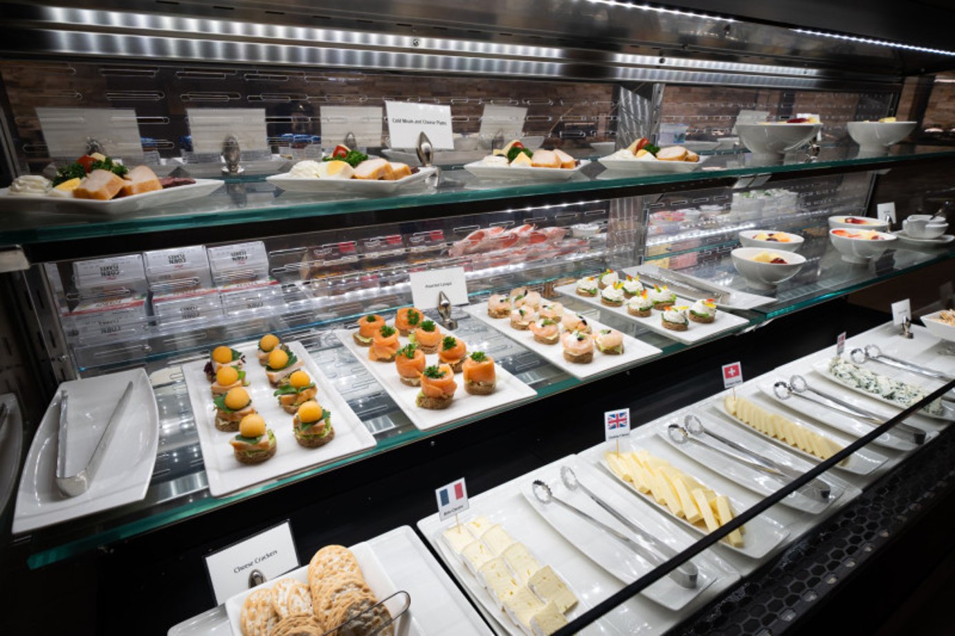 Gourmet buffet selection at Emirates Lounge Satellite 1 Bangkok Suvarnabhumi Airport featuring international cheeses, canapés, and fresh fruit platters.