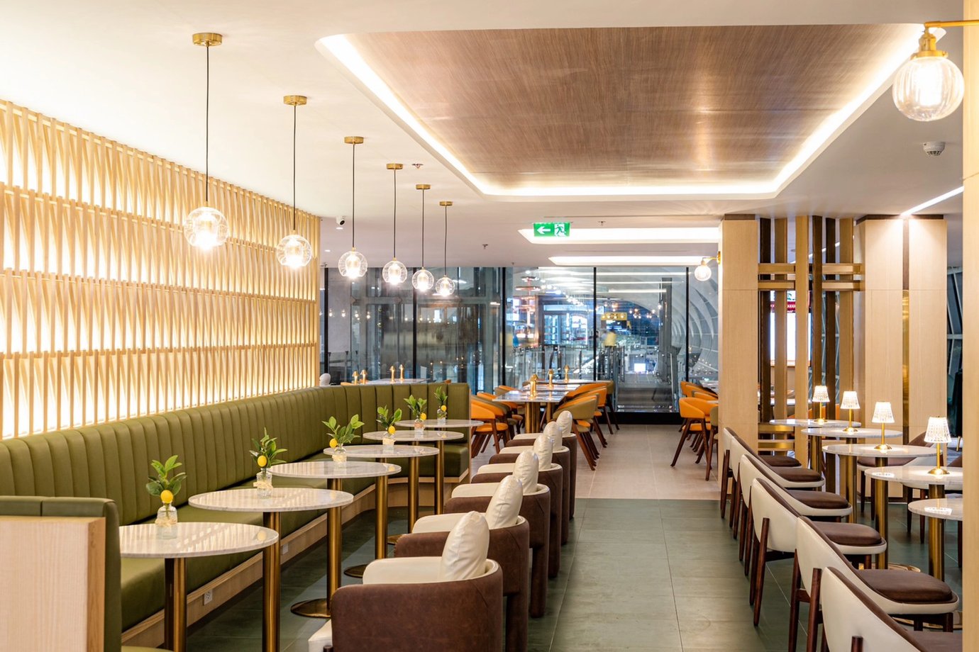 Elegant interior of The Coral Finest Business Class Lounge at Bangkok Suvarnabhumi Airport, featuring marble tables, green and brown upholstered seating.