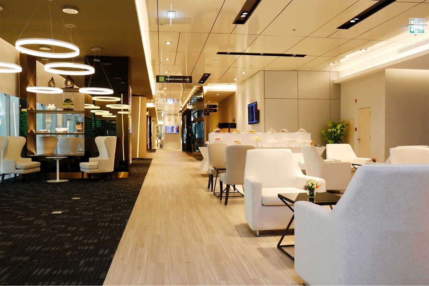 Miracle Business Class Lounge Concourse D Bangkok Suvarnabhumi Airport featuring modern seating, elegant ring lighting, a self-serve buffet counter, and bright interiors.