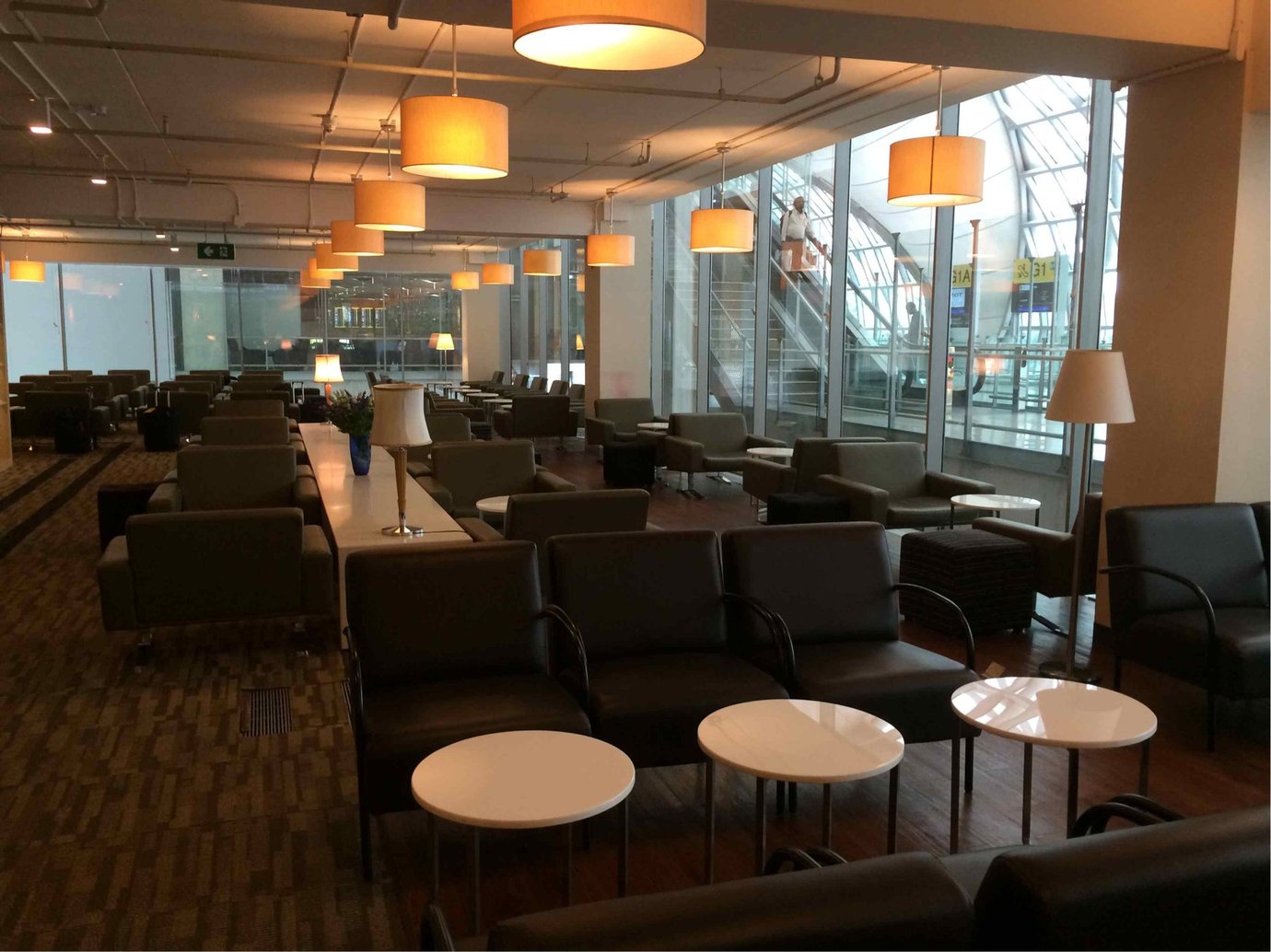 Spacious seating area at Miracle Business Class Lounge Concourse G Bangkok Suvarnabhumi Airport featuring leather armchairs, soft lighting, and large glass windows overlooking the terminal concourse.