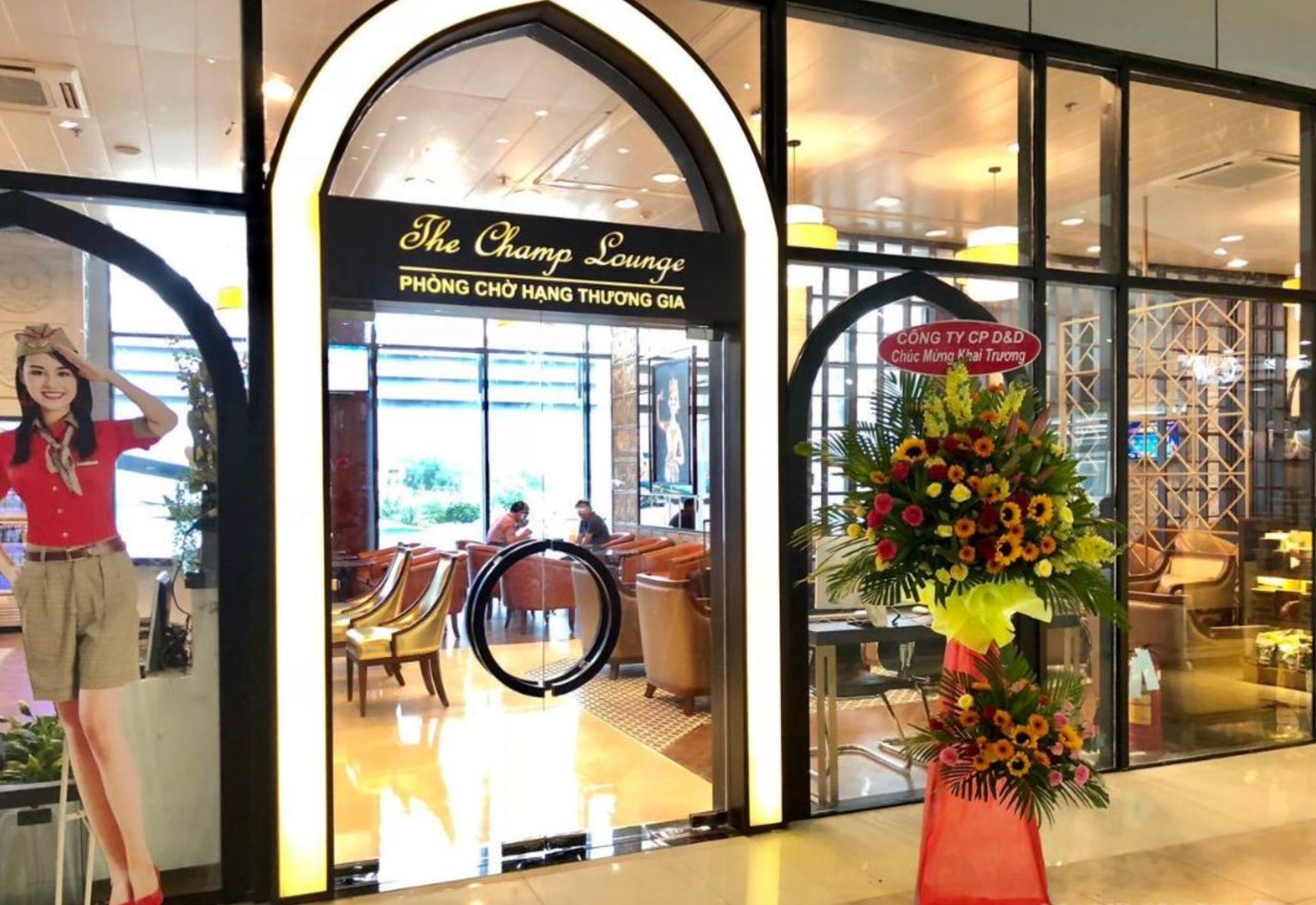 Entrance to The Champ Lounge at Cam Ranh International Airport Terminal 1 with bright floral display and modern glass design.