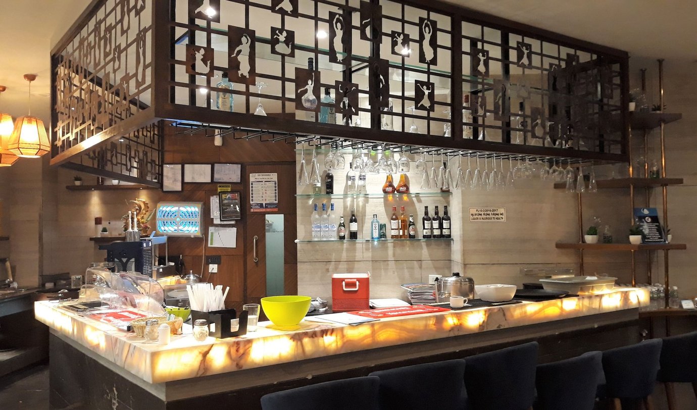 TFS Travel Club Lounge Chennai Terminal 1 bar area with illuminated onyx counter, hanging glass rack and premium liquor display.