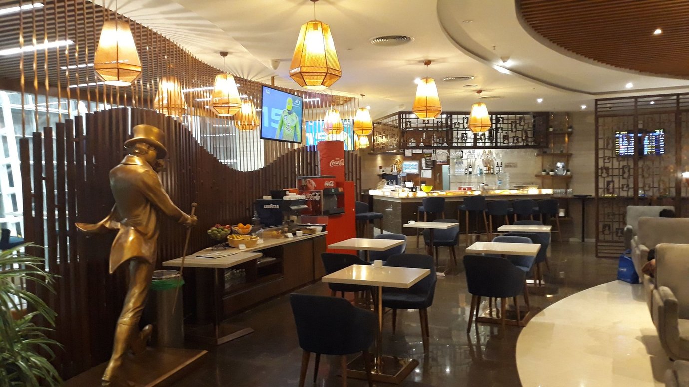 TFS Travel Club Lounge Chennai Terminal 1 featuring warm ambient lighting, dining tables, bar counter and stylish modern seating.