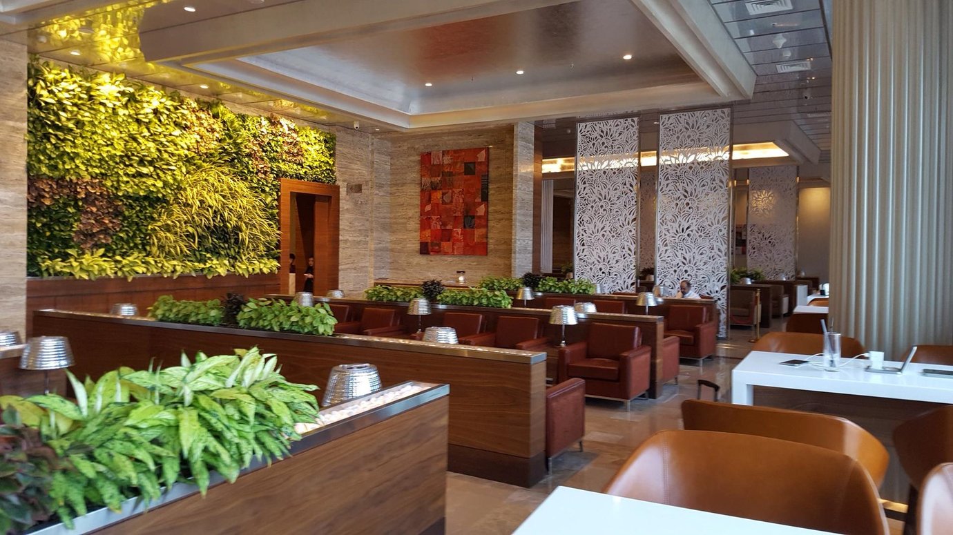 Adani Lounge at Mumbai Airport T2 Domestic, featuring leather armchairs, modern wooden partitions, lush indoor greenery, and a stylish seating area with natural light. Adani Lounge at Mumbai Airport T2 Domestic, featuring leather armchairs, modern wooden partitions, lush indoor greenery, and a stylish seating area with natural light.