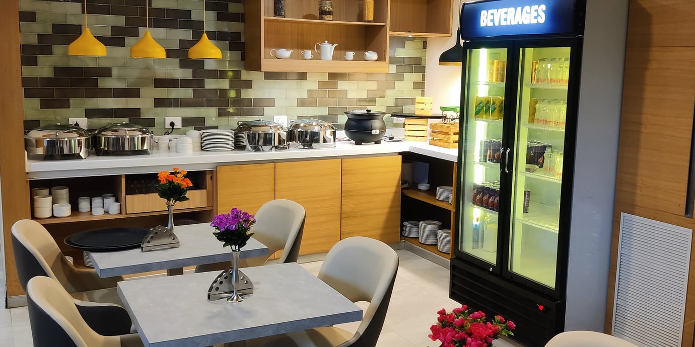 Buffet counter at Aviserv East Lounge Mumbai Airport with hot dishes, soup station, beverage fridge, and modern seating area. Buffet counter at Aviserv East Lounge Mumbai Airport with hot dishes, soup station, beverage fridge, and modern seating area.