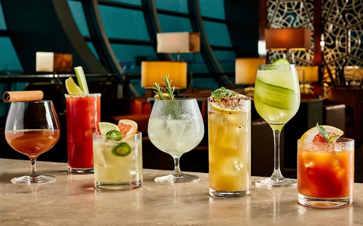 A curated lineup of colorful cocktails and mocktails on a marble counter at the Emirates First Class Lounge bar in Dubai International Airport. A curated lineup of colorful cocktails and mocktails on a marble counter at the Emirates First Class Lounge bar in Dubai International Airport.