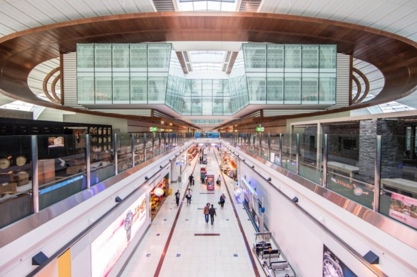 Interior view of Dubai International Airport’s Terminal 3, showcasing the sleek modern architecture of the concourse. The image looks down onto a central shopping and dining walkway lined with luxury stores and cafés. Interior view of Dubai International Airport’s Terminal 3, showcasing the sleek modern architecture of the concourse. The image looks down onto a central shopping and dining walkway lined with luxury stores and cafés.