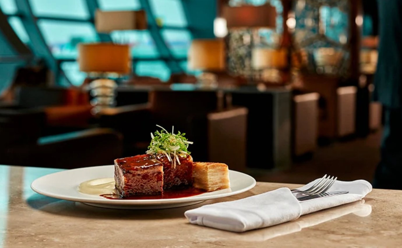 A gourmet plated meal at the Emirates First Class Lounge in Dubai International Airport. The dish features a tender beef short rib topped with glossy sauce and garnished with microgreens, served alongside a layered potato gratin. A gourmet plated meal at the Emirates First Class Lounge in Dubai International Airport. The dish features a tender beef short rib topped with glossy sauce and garnished with microgreens, served alongside a layered potato gratin.