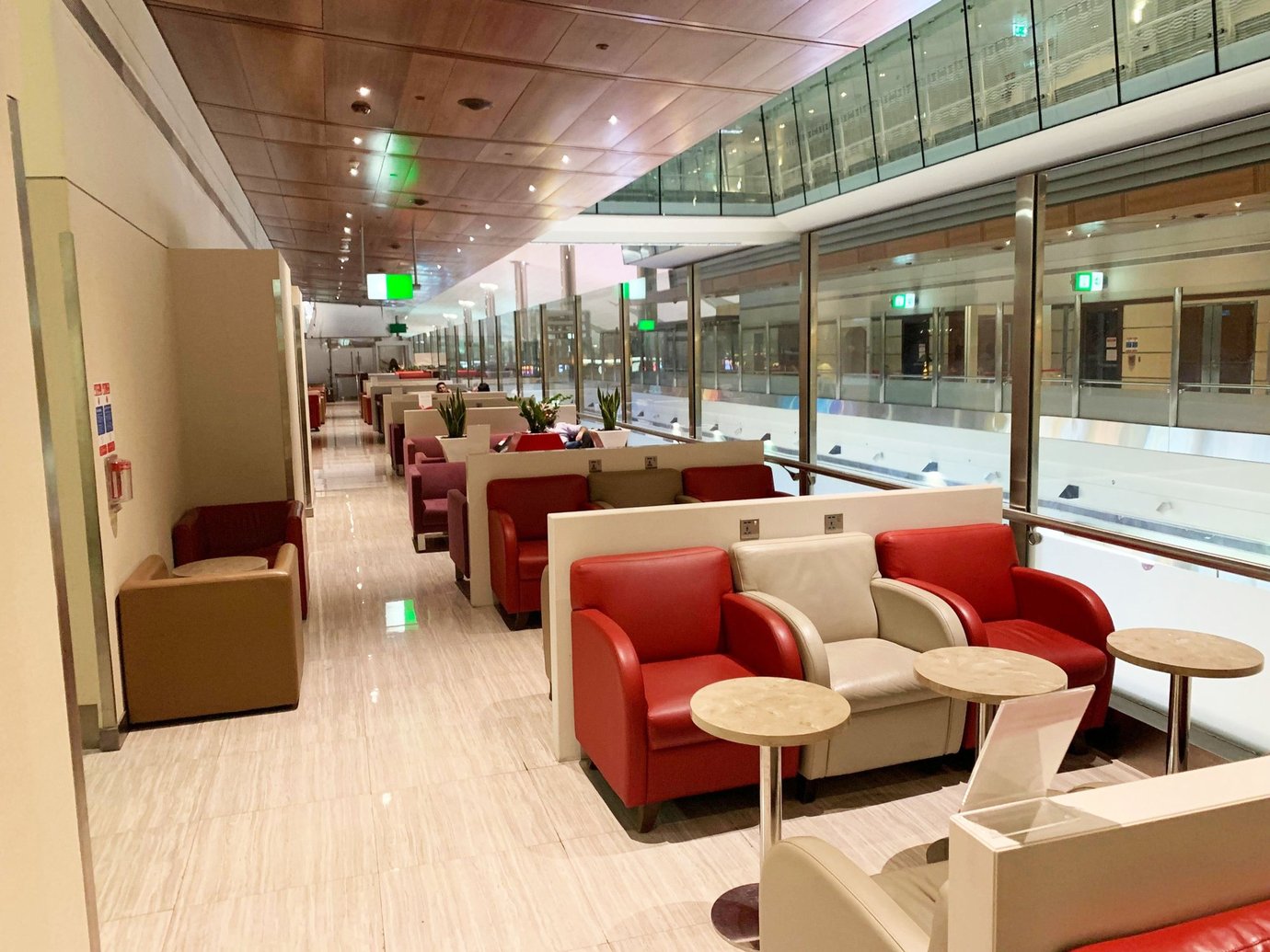 Seating area inside the Marhaba Lounge at Dubai International Airport Terminal 3 Concourse B, featuring red and beige leather armchairs, marble side tables, and floor-to-ceiling glass walls overlooking the terminal concourse. Seating area inside the Marhaba Lounge at Dubai International Airport Terminal 3 Concourse B, featuring red and beige leather armchairs, marble side tables, and floor-to-ceiling glass walls overlooking the terminal concourse.