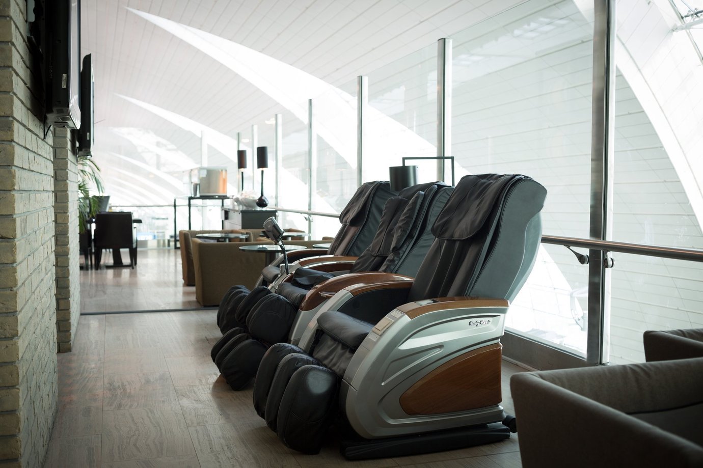 Massage chairs inside the Ahlan Lounge at Dubai International Airport Terminal 3 Concourse B, featuring modern reclining seats with wood accents overlooking the bright glass architecture of the terminal. Massage chairs inside the Ahlan Lounge at Dubai International Airport Terminal 3 Concourse B, featuring modern reclining seats with wood accents overlooking the bright glass architecture of the terminal.