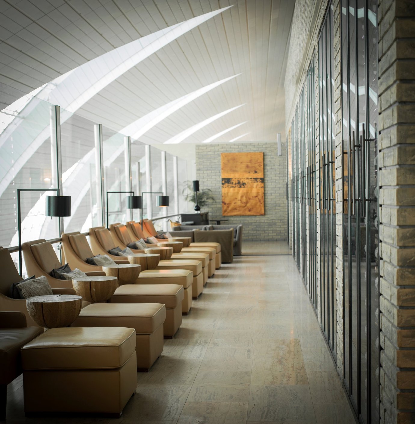 Row of tan leather lounge chairs inside the Ahlan Lounge at Dubai International Airport Terminal 3 Concourse B, featuring floor-to-ceiling glass windows, warm lighting, and modern décor for a serene relaxation space Row of tan leather lounge chairs inside the Ahlan Lounge at Dubai International Airport Terminal 3 Concourse B, featuring floor-to-ceiling glass windows, warm lighting, and modern décor for a serene relaxation space