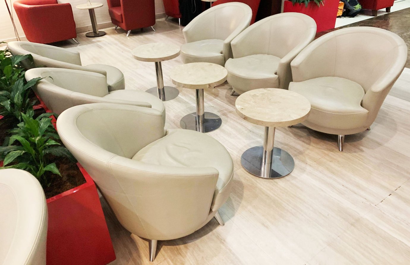 Seating area inside the Marhaba Lounge at Dubai International Airport Terminal 3 Concourse C, featuring curved beige leather chairs, round marble tables, and decorative planters creating a relaxed and modern atmosphere. Seating area inside the Marhaba Lounge at Dubai International Airport Terminal 3 Concourse C, featuring curved beige leather chairs, round marble tables, and decorative planters creating a relaxed and modern atmosphere.