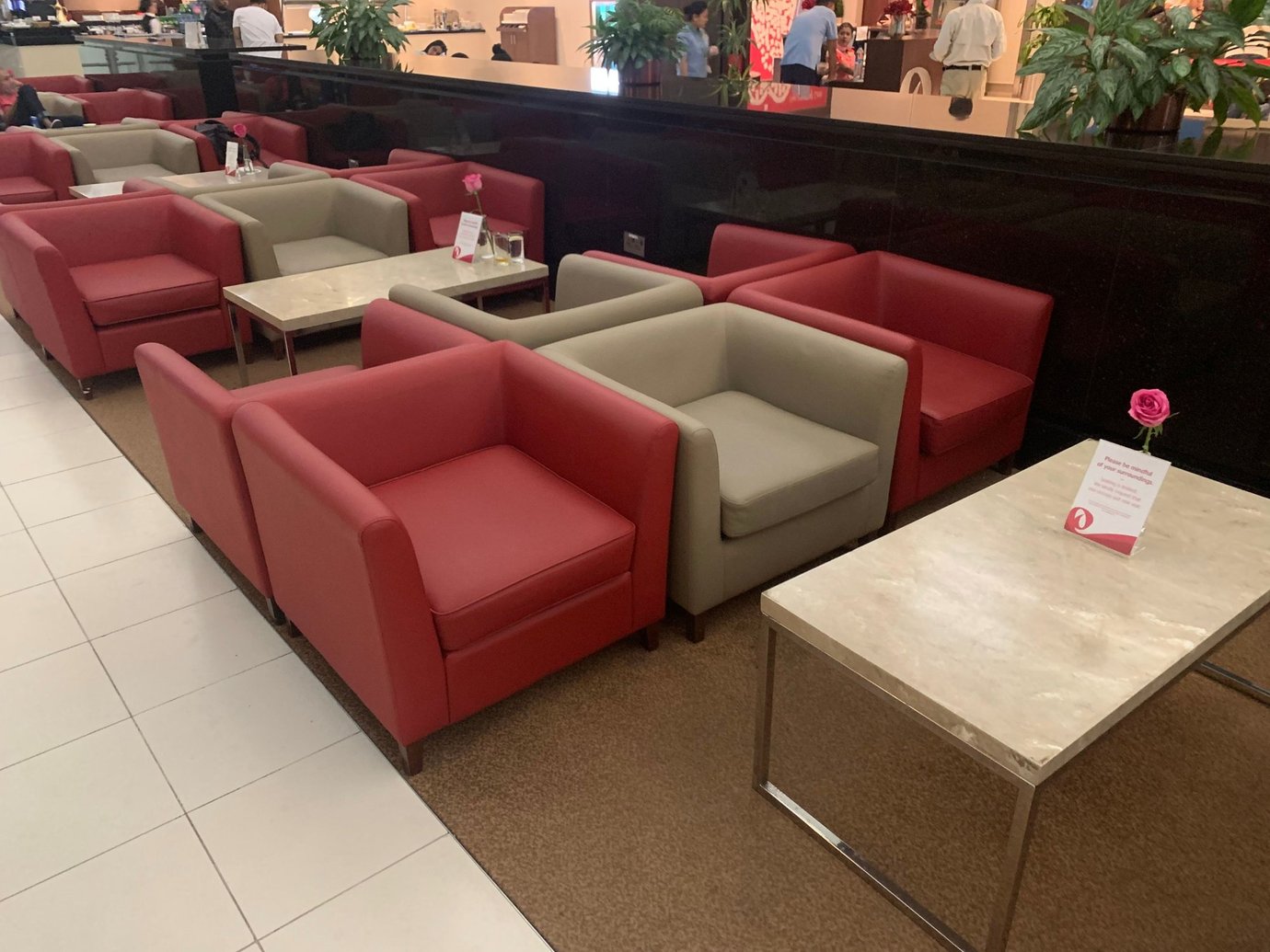 Seating area inside the Marhaba Lounge at Dubai International Airport Terminal 3 Concourse A, featuring modern red and beige armchairs with marble tables, soft lighting, and a relaxed atmosphere near the refreshment counter. Seating area inside the Marhaba Lounge at Dubai International Airport Terminal 3 Concourse A, featuring modern red and beige armchairs with marble tables, soft lighting, and a relaxed atmosphere near the refreshment counter.