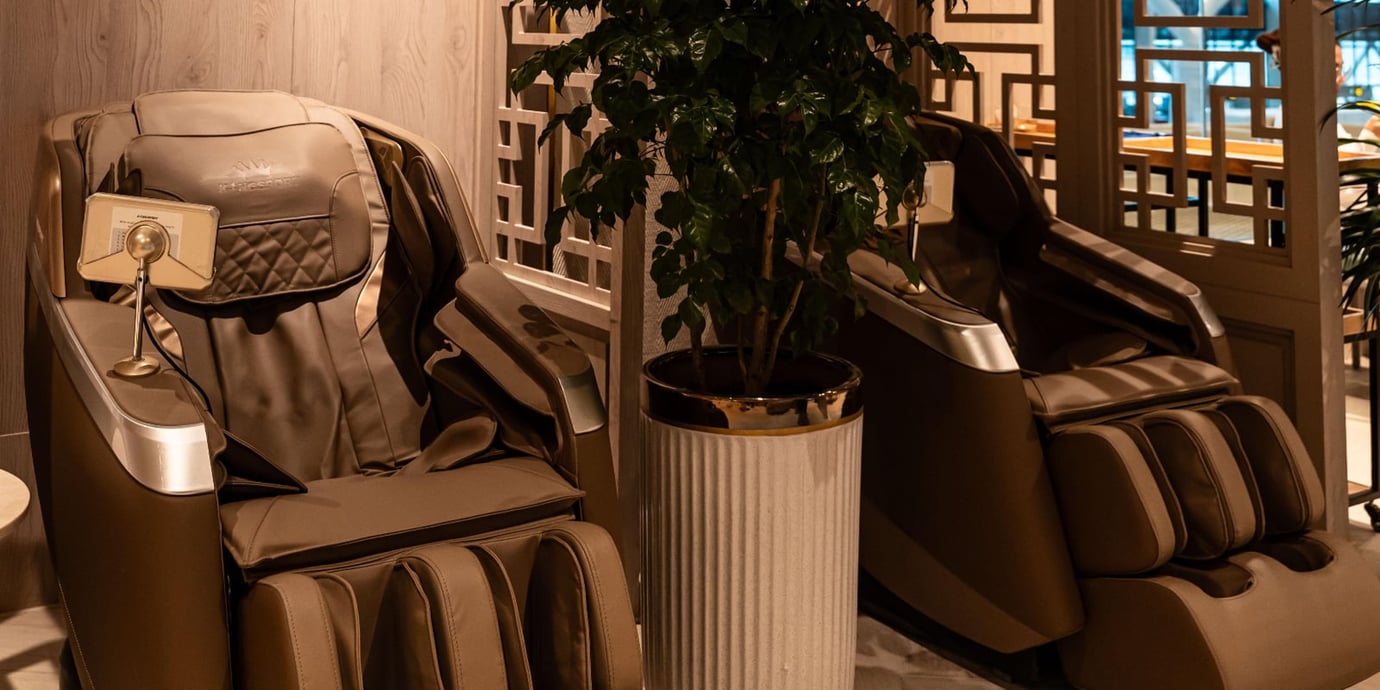 Massage chair area inside the SH Premium Lounge at Tan Son Nhat Airport, featuring two full-body reclining massage chairs in a softly lit corner. Massage chair area inside the SH Premium Lounge at Tan Son Nhat Airport, featuring two full-body reclining massage chairs in a softly lit corner.