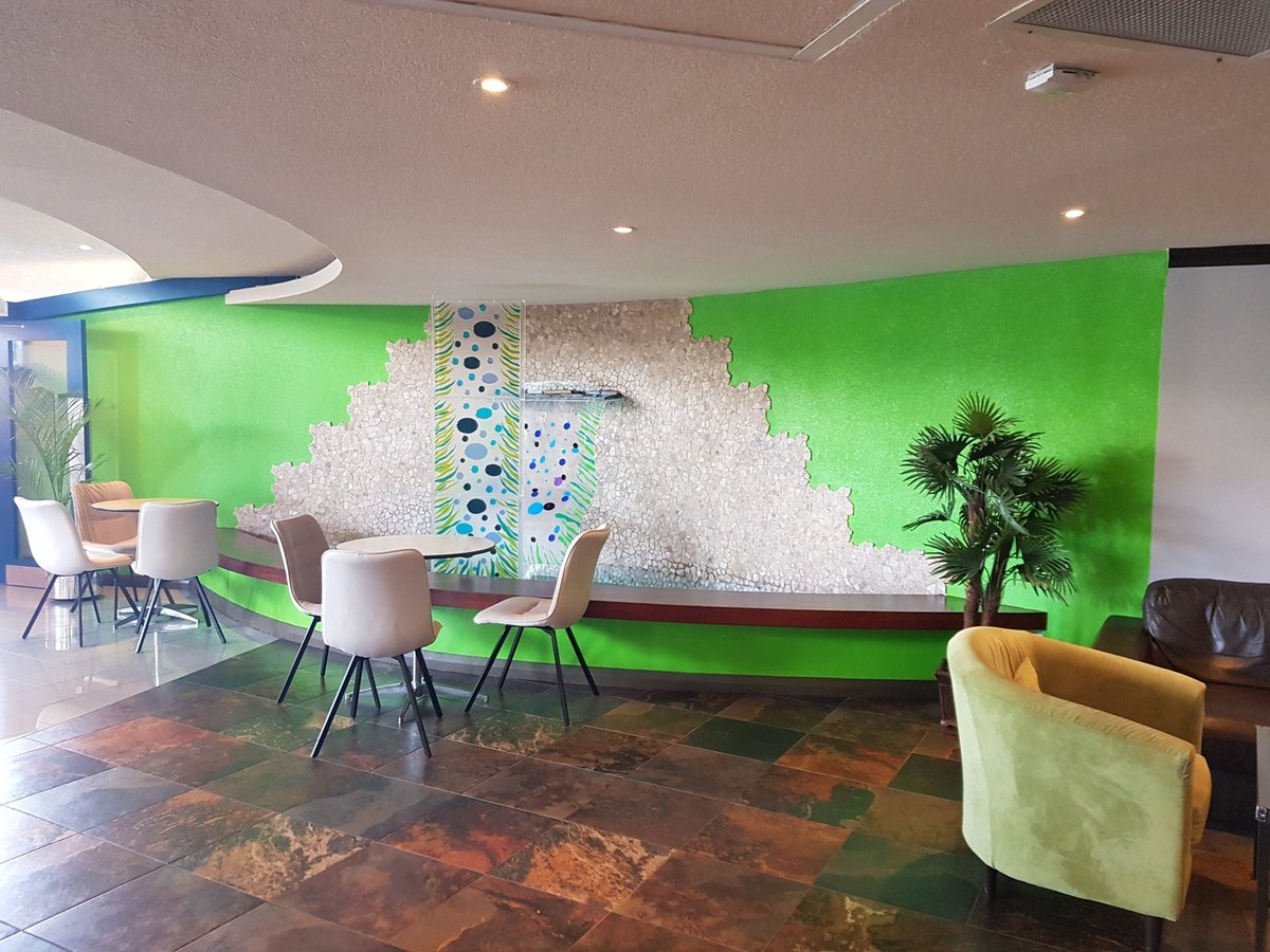 Modern seating area in the Airlines Executive Lounge at Grantley Adams International Airport, featuring stylish chairs, a decorative green accent wall, and tropical indoor plants.