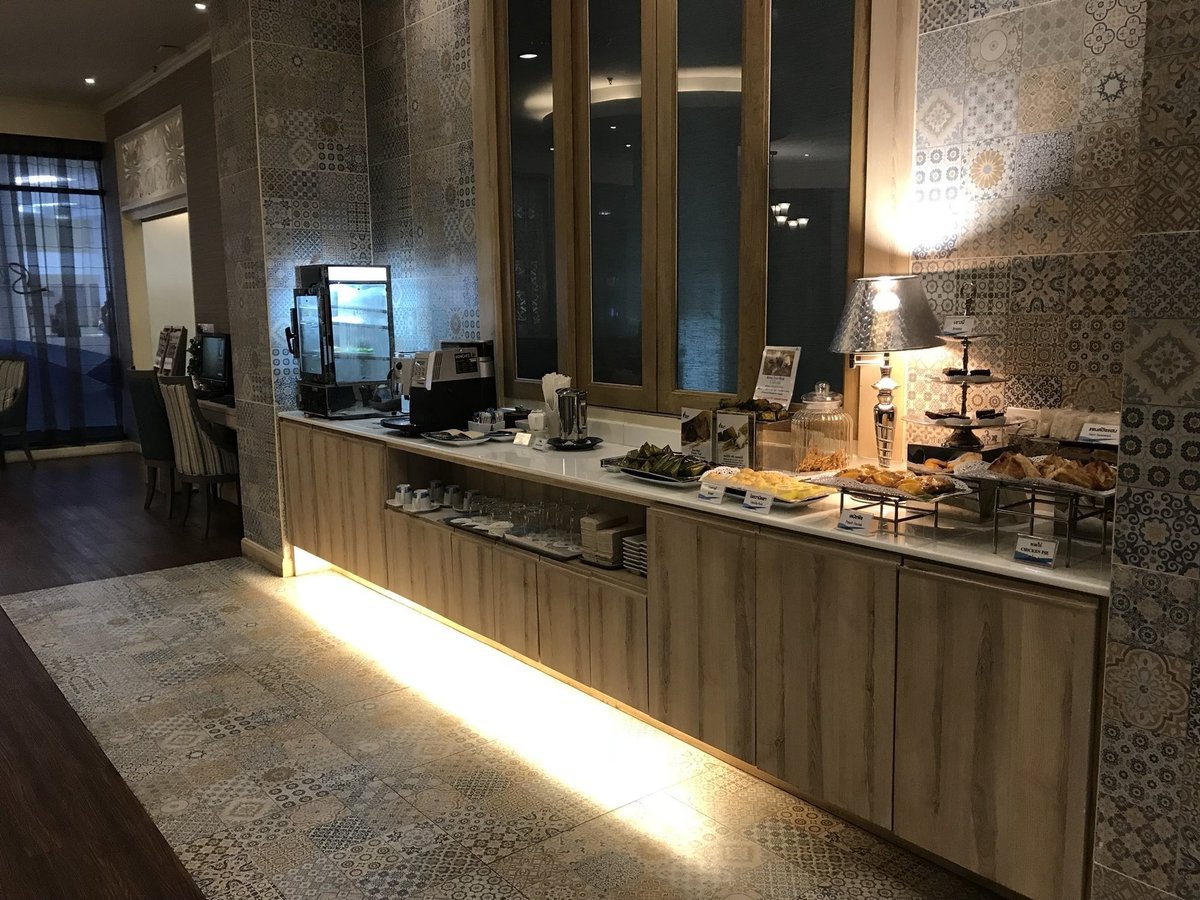 Buffet counter at the Blue Ribbon Club Lounge in Chiang Mai International Airport (CNX), featuring a selection of pastries, Thai snacks, a coffee and tea station, and decorative patterned tile walls in a warm, modern setting.