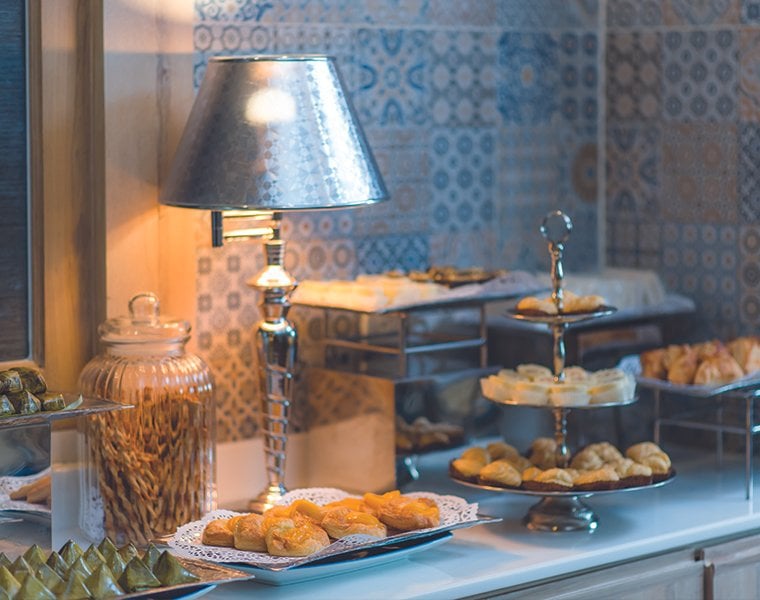 A selection of food items and pastries from the buffet at Bangkok Airways Blue Ribbon Lounge. There is also a silver lamp to illuminate the counter.