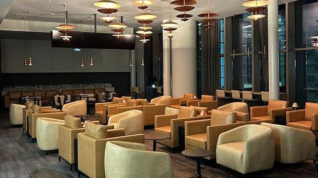 Evening view of Çelebi Platinum International Lounge at Çukurova International Airport, showcasing warm ambient lighting, comfortable lounge seating, and floor-to-ceiling windows for a relaxed travel atmosphere.