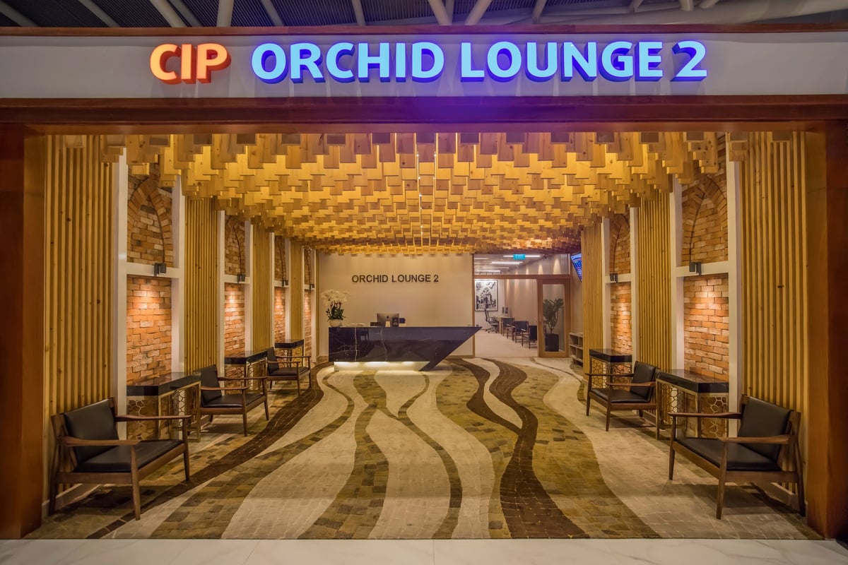 Entrance to CIP Orchid Lounge 2 at Da Nang International Airport, featuring a warm wood ceiling design, brick accent walls, and modern reception area lighting.