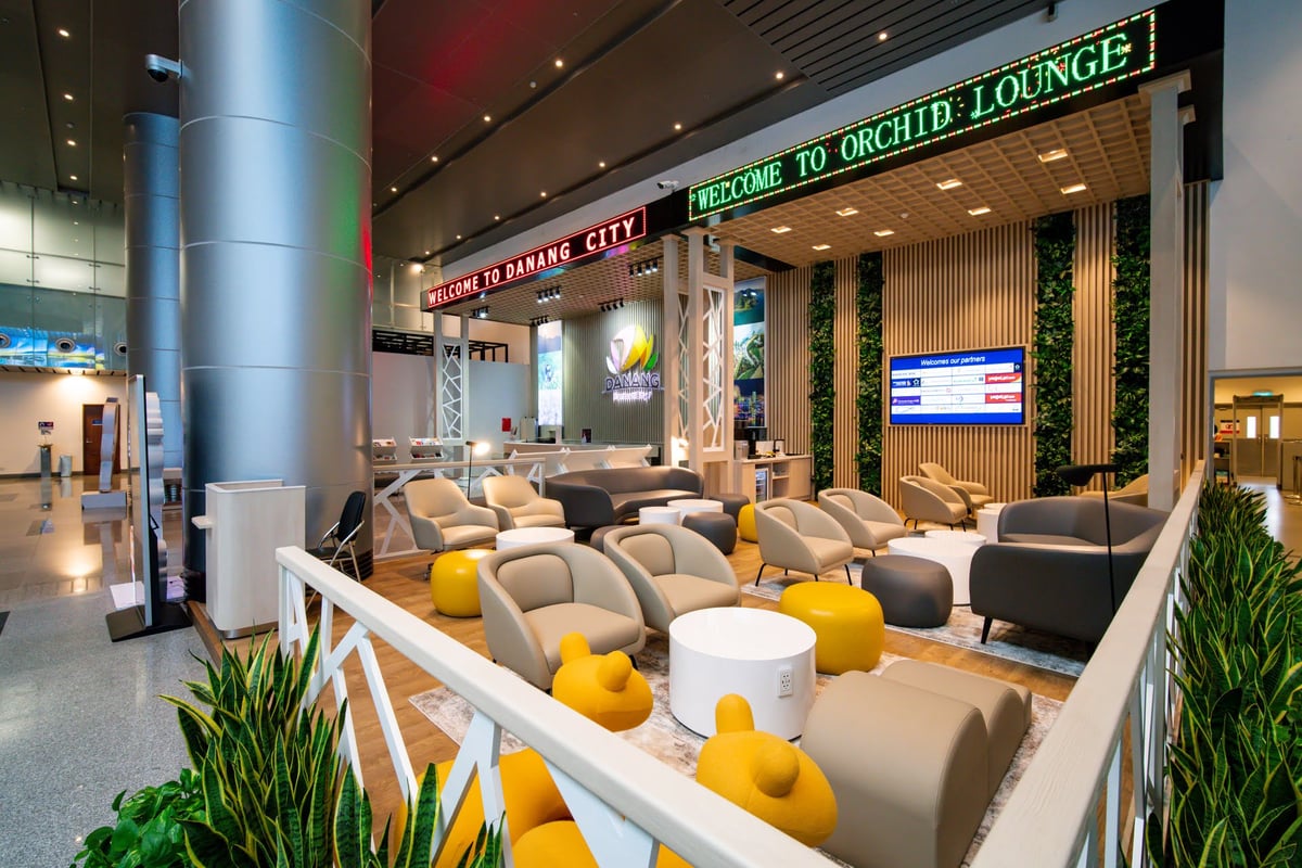 Arrival seating area at CIP Orchid Lounge 3 in Da Nang International Airport, featuring modern lounge chairs, greenery, and digital welcome signage in the baggage claim zone.