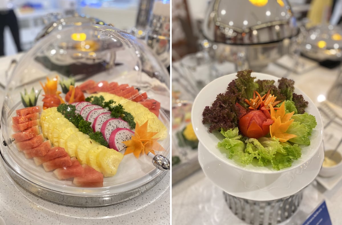 Colourful fruit and vegetable platters at Vietnam Airlines Lotus Lounge at Da Nang International Airport, featuring fresh watermelon, pineapple, dragon fruit, and decorative salad arrangements on a buffet display.