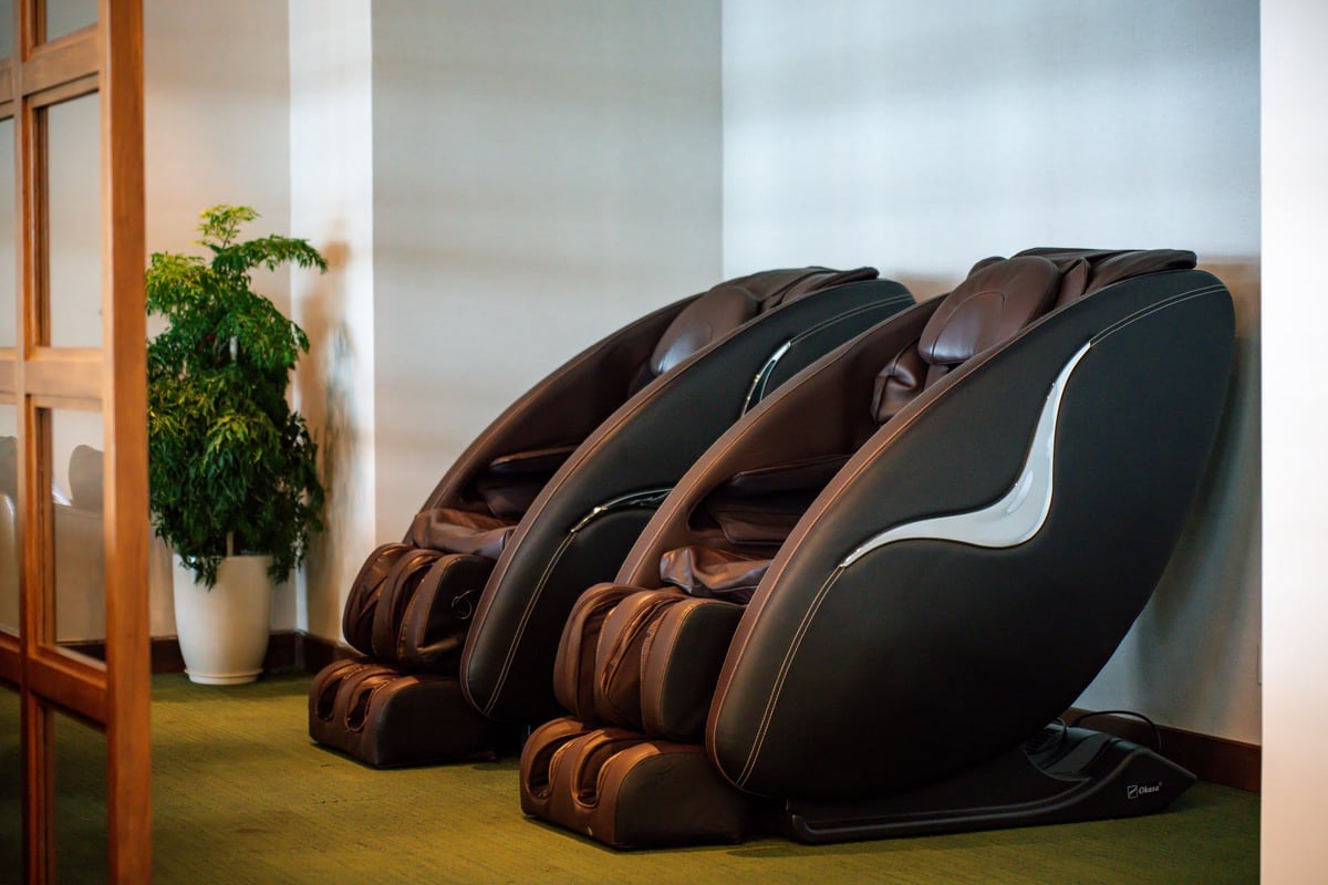 Two luxurious leather massage chairs in a serene relaxation zone of CIP Orchid Lounge 1 at Da Nang International Airport Terminal 2, set against a minimalist wall with warm lighting and a decorative indoor plant.