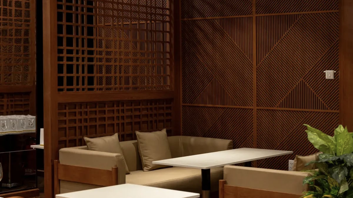 Cozy corner seating with beige sofas and wooden accents inside SH Premium Lounge at Da Nang International Airport, featuring modern lighting, geometric wood paneling, and a relaxing atmosphere.
