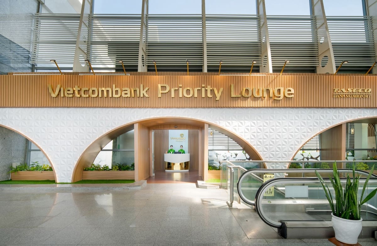 Entrance of Vietcombank Priority Lounge at Da Nang International Airport (Domestic Terminal), showcasing a stylish modern design with white geometric walls, wood accents, gold signage, and a welcoming reception area for Vietcombank cardholders.