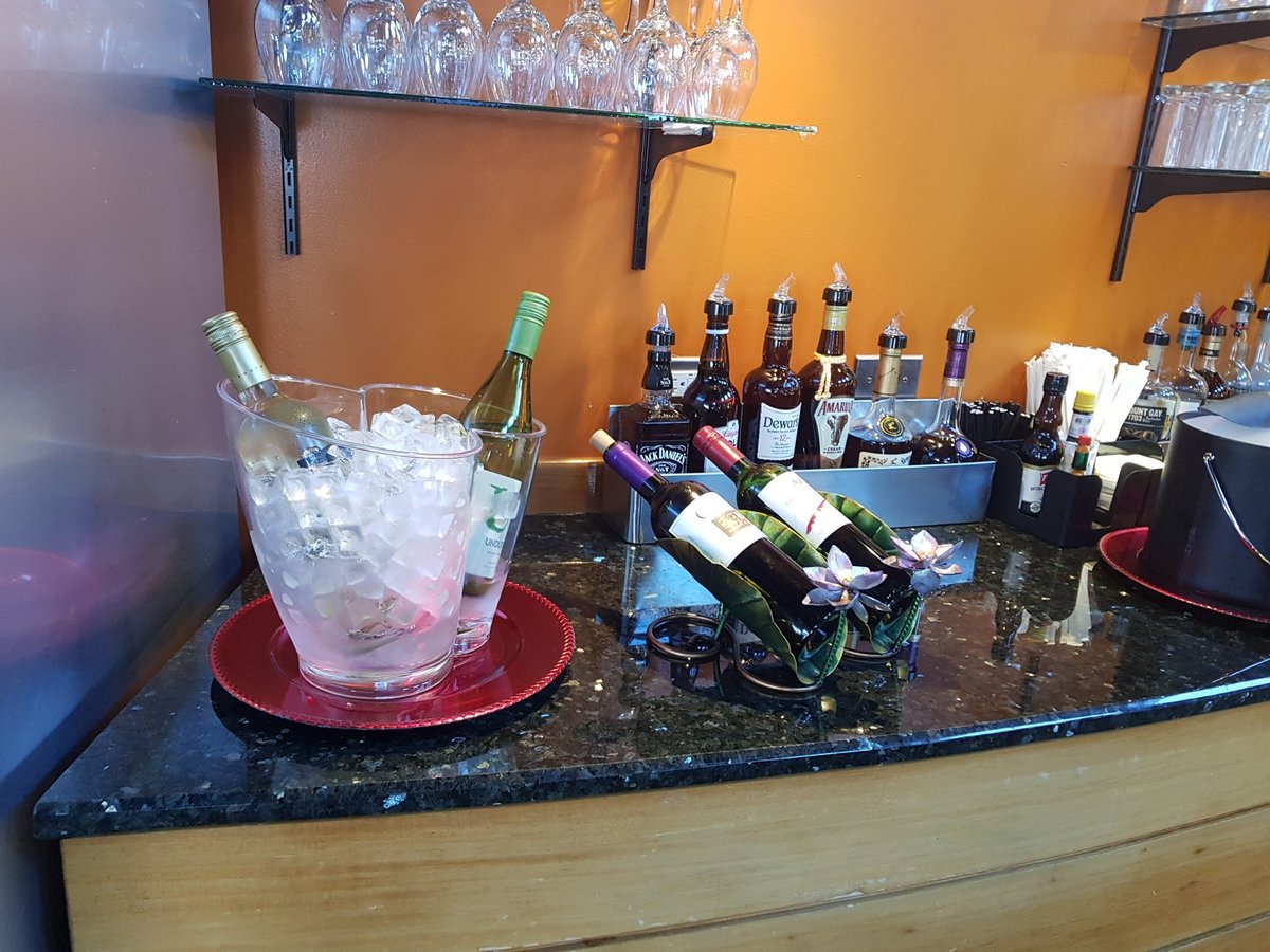 Beverage station at the Airlines Executive Lounge in Grantley Adams International Airport, showcasing a selection of wines, spirits, and ice-chilled white wine bottles on a sleek granite counter.