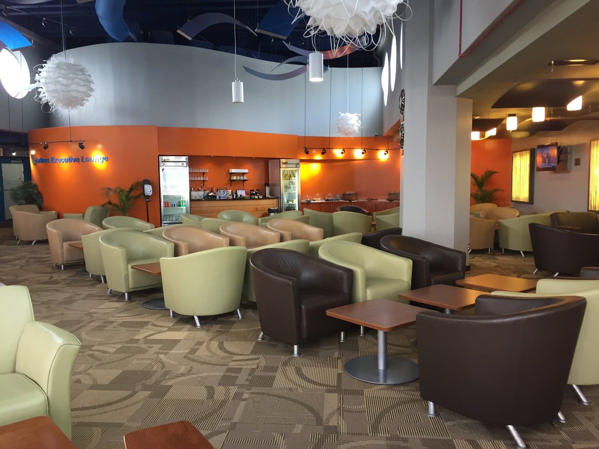 Interior of the Airlines Executive Lounge at Grantley Adams International Airport in Barbados, featuring modern armchairs, warm lighting, beverage station, and relaxed atmosphere for travelers.