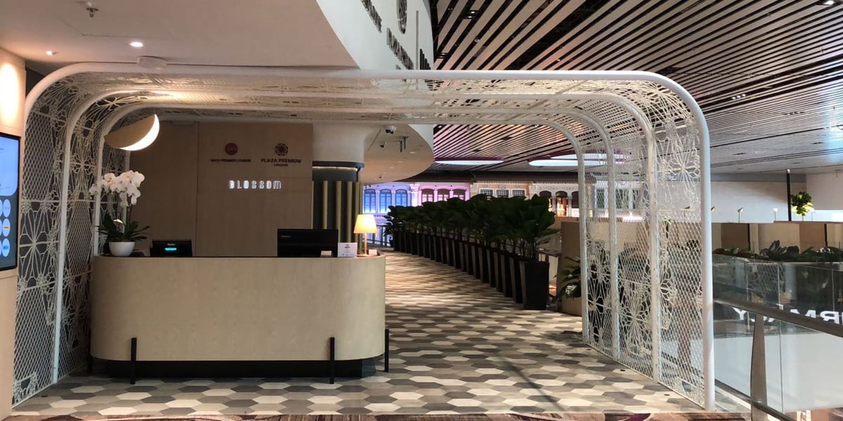 Entrance of Blossom Lounge at Changi Airport Terminal 4 with modern reception desk, orchid decor, and stylish interior design.