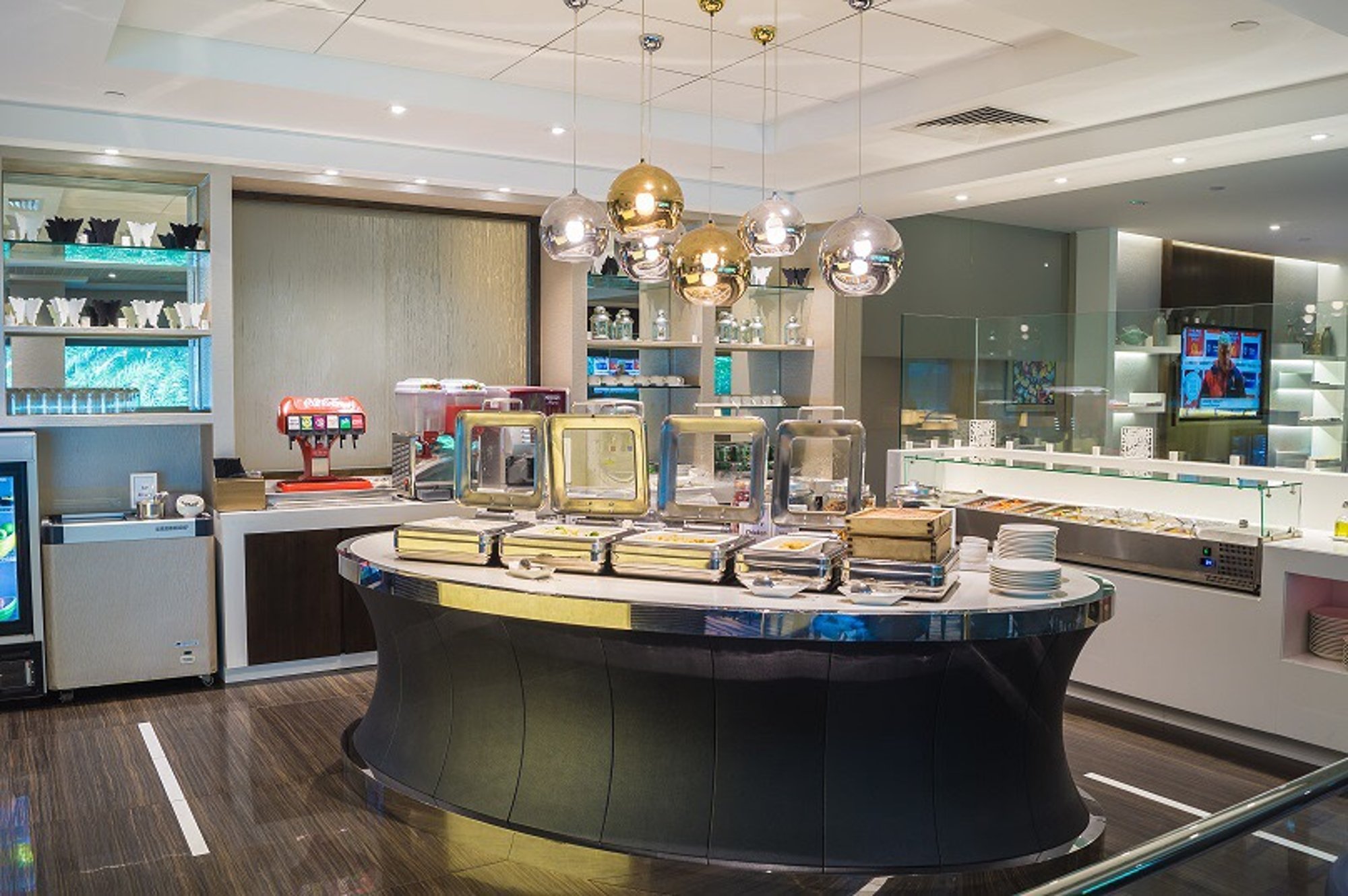 Buffet dining area at Ambassador Transit Lounge in Singapore Changi Airport Terminal 3, featuring hot food counters, beverage machines, and modern decor.