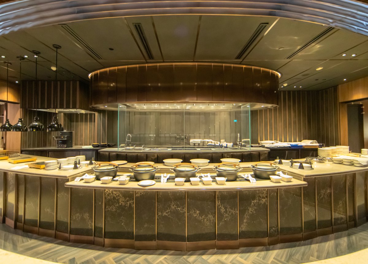 Buffet dining area at SilverKris First Class Lounge in Singapore Changi Airport, featuring a marble counter, warm lighting, and an open kitchen design.