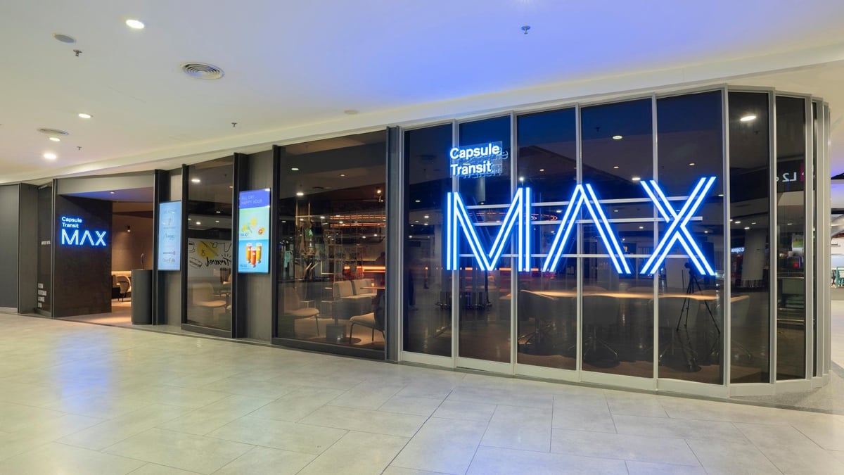 Entrance of Capsule Transit MAX at KLIA Terminal 2, featuring a sleek glass exterior and prominent blue neon signage that reads 