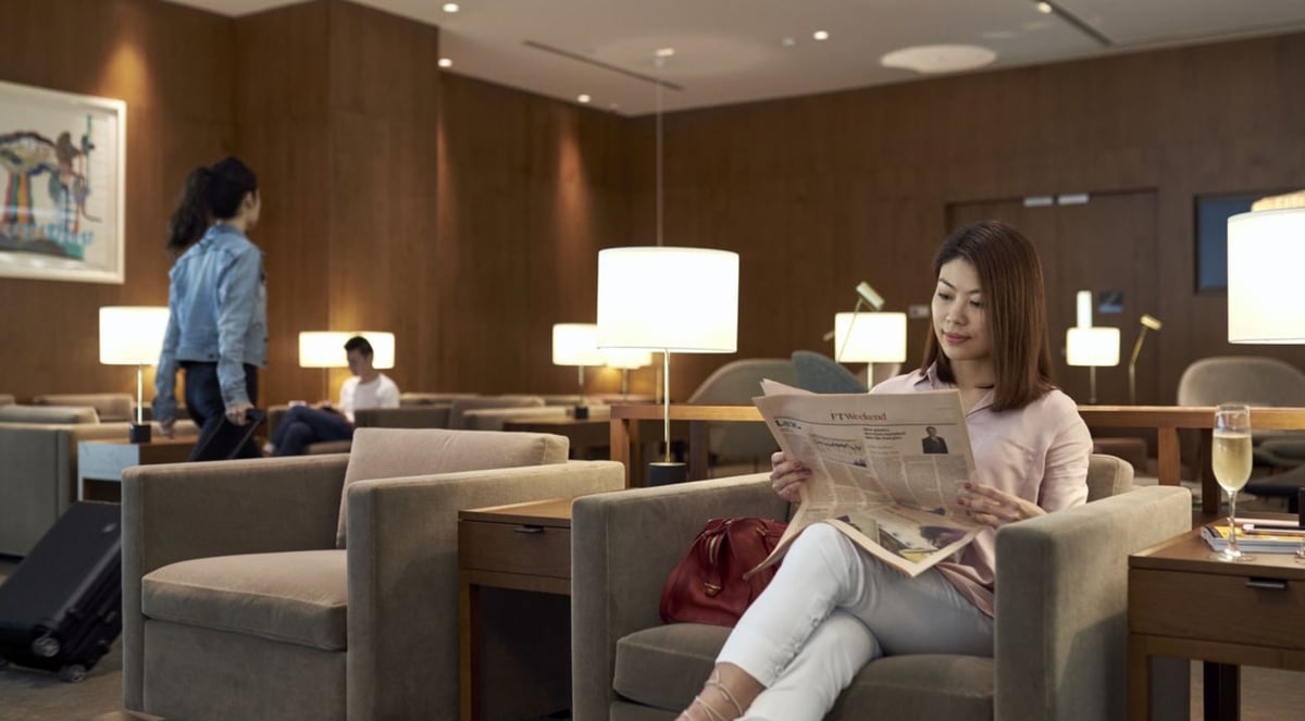Passenger relaxing with a newspaper in the seating area of Cathay Pacific Lounge at Changi Airport Terminal 4.