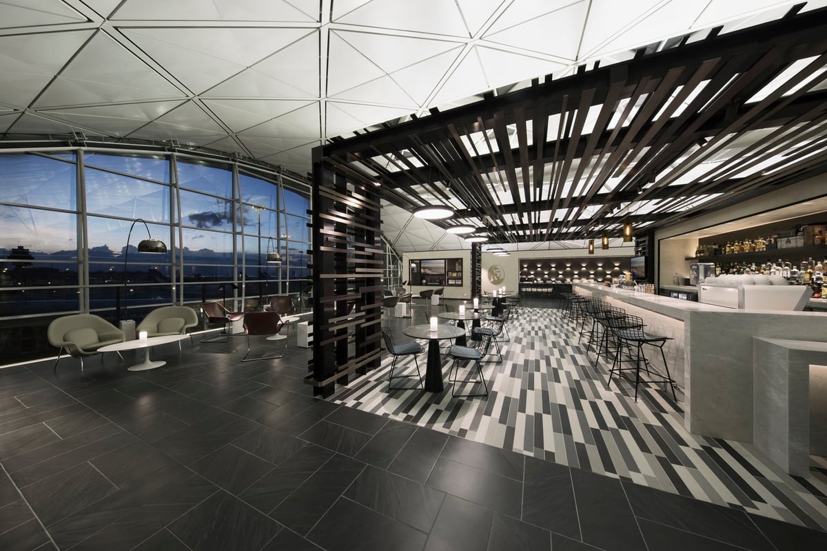 Exterior view of the Centurion Lounge by American Express at Hong Kong International Airport, showcasing its elevated location, geometric ceiling, and modern glass façade with illuminated Amex signage
