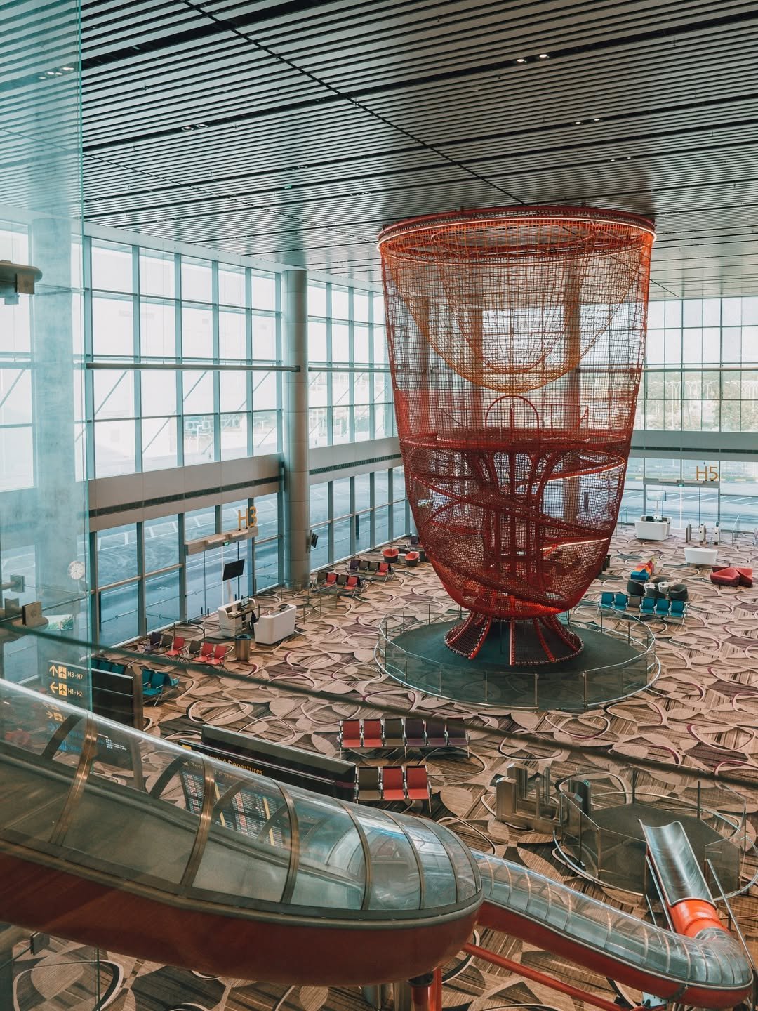 Chandelier playground at Changi Airport Terminal 4 Singapore with climbing net structure and giant slide attraction in spacious terminal area.