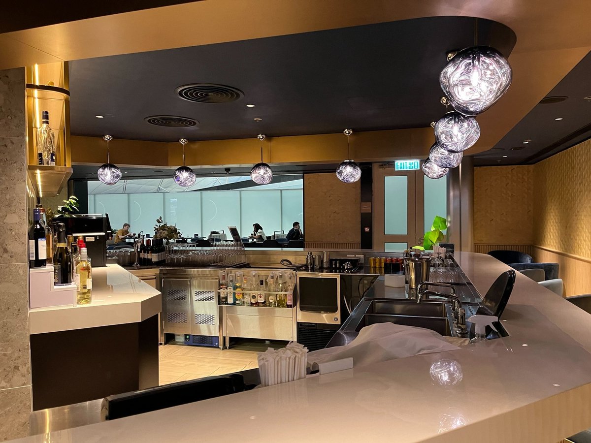 Elegant bar area with crystal pendant lights and a selection of wines and spirits at the Chase Sapphire Lounge Hong Kong Airport.