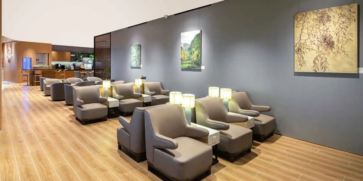 The photo features the seating area of the Plaza Premium Lounge at Chongqing Jiangbei International Airport, highlighting comfortable recliners and a serene atmosphere enhanced by ambient lighting and modern decor.