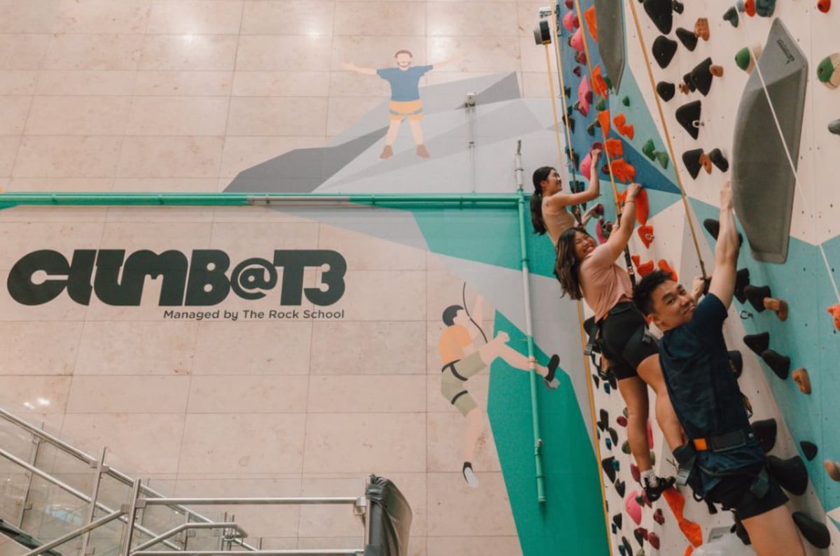 Travelers enjoying the Climb@T3 rock climbing wall at Singapore Changi Airport Terminal 3, an adventure attraction managed by The Rock School.