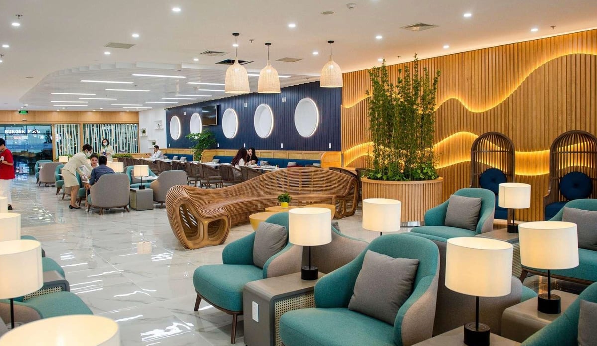Bamboo Airways First Lounge at Hanoi Airport with a modern and vibrant interior featuring teal and gray armchairs, wooden accents, and decorative wave-patterned wall lighting.