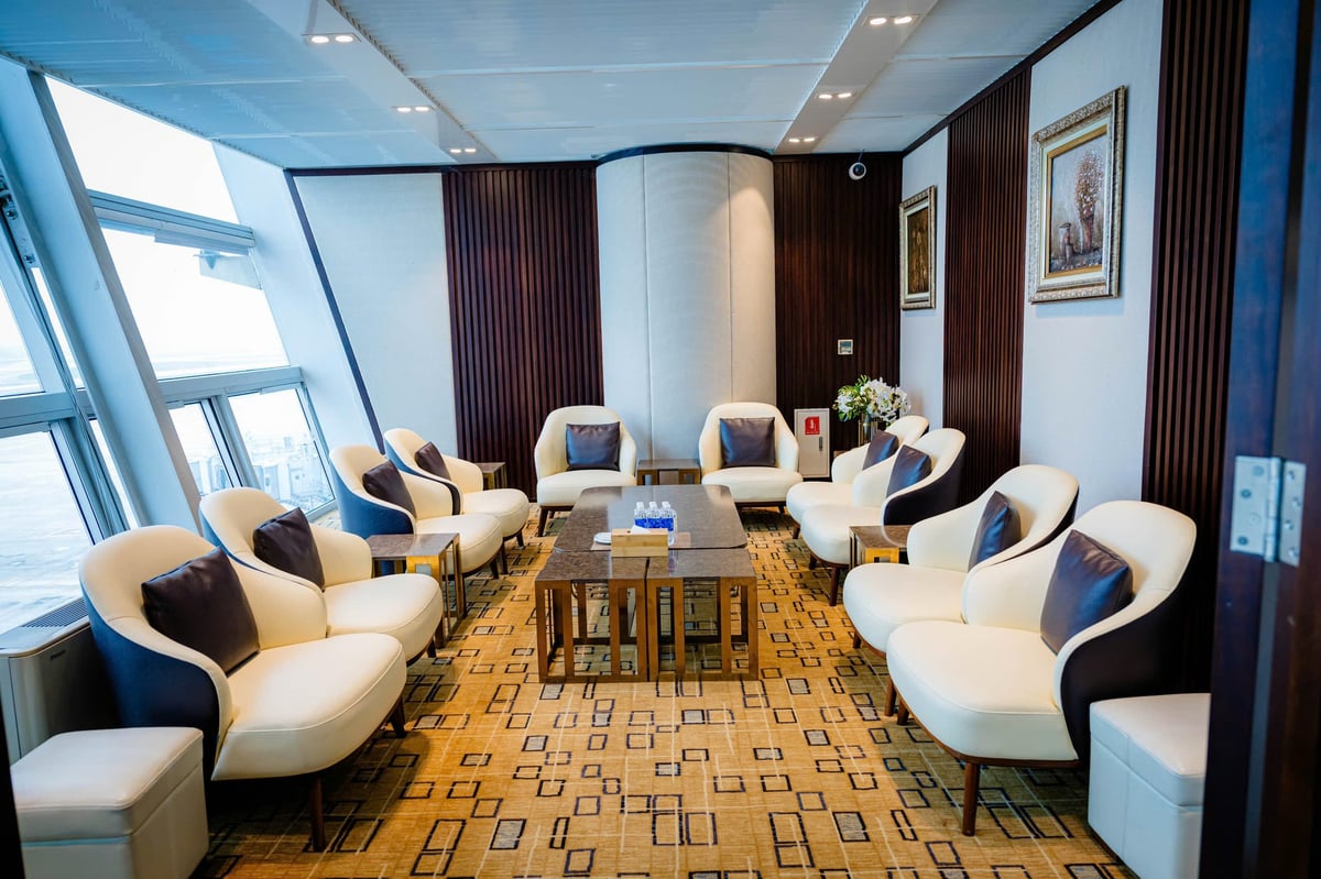 Private rest area in the ACV Business Lounge at Hanoi Noi Bai International Airport. The room features a large table surrounded by plush cream-colored armchairs with dark cushions, warm wooden paneling, and decorative wall art.