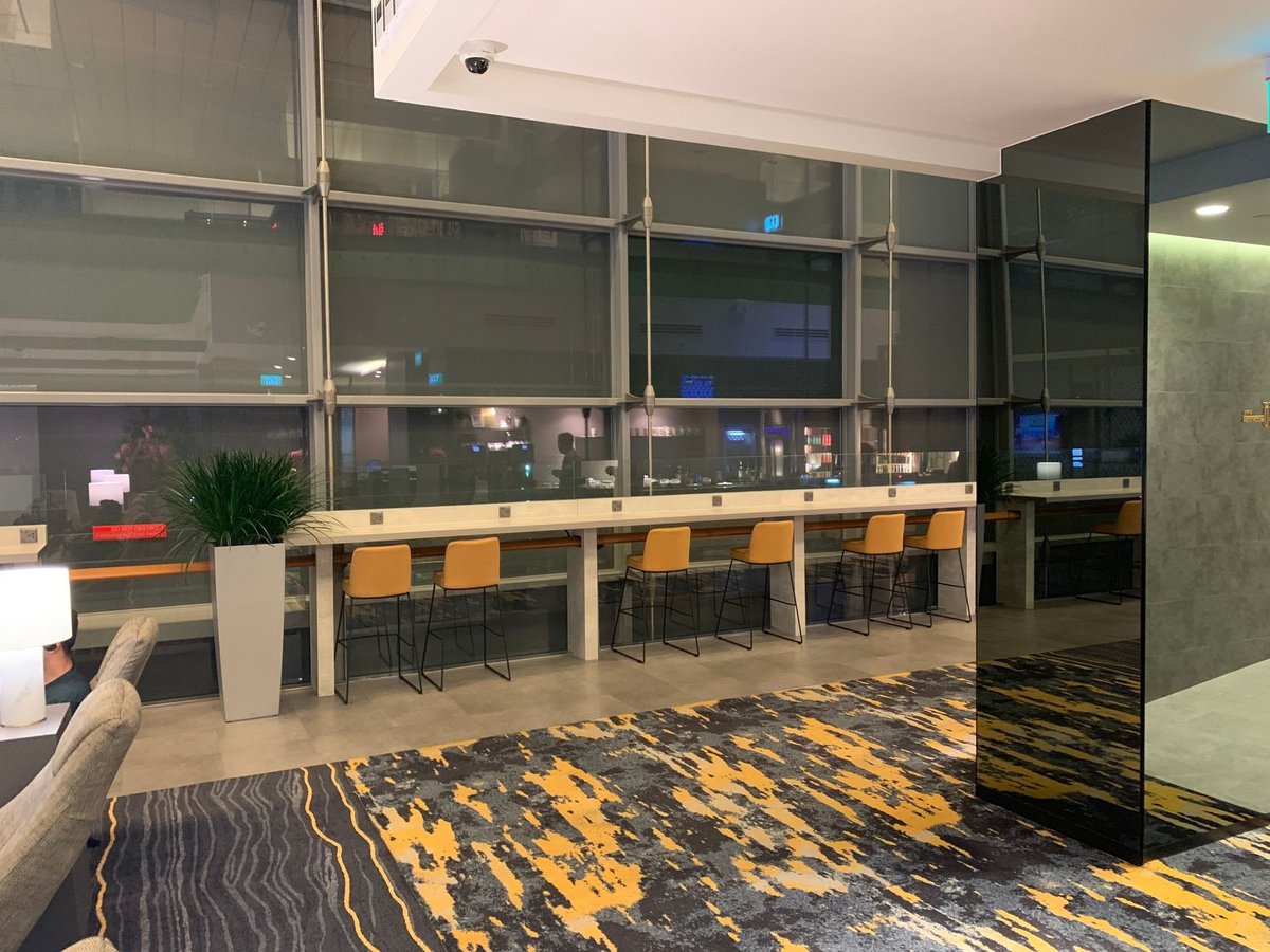 Dining and work area with tarmac views inside Marhaba Lounge at Singapore Changi Airport Terminal 3, featuring high chairs, charging outlets, and modern design.