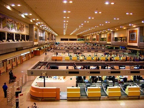 Interior View of Don Mueang International Airport with numerous unoccupied counters, a large hall space and with only a few individuals present.
