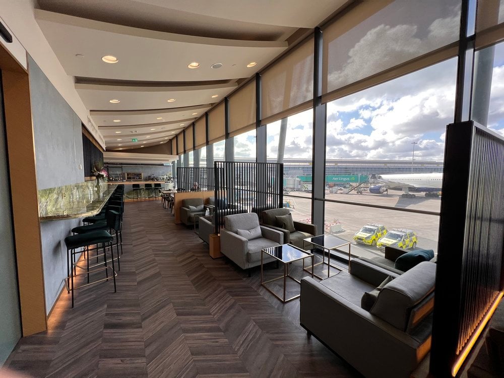 Elegant East Lounge at Dublin Airport with plush sofas, designer lighting, and a view of aircraft on the tarmac.